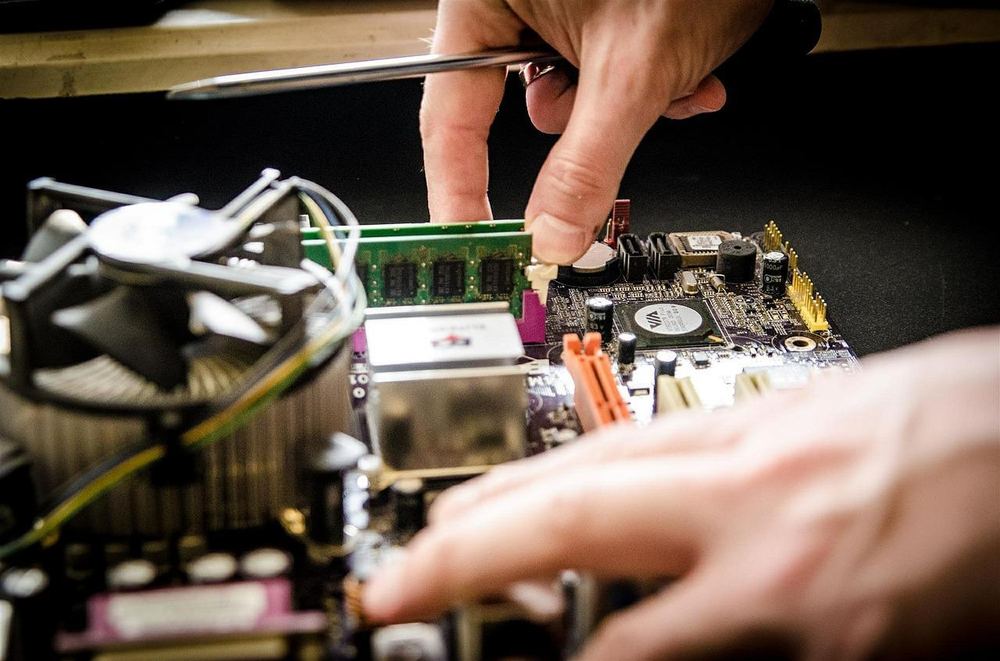 Technicien installant une barrette de mémoire sur un poste de travail